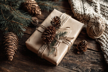 Rustic christmas gift wrapped in kraft paper with pine cones