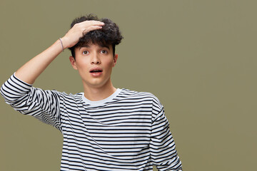 surprised man in striped shirt holding head with hand isolated on green background, young, casual outfit, expressive face, studio portrait, reaction concept