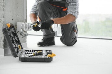 African American electrician replacing socket in room