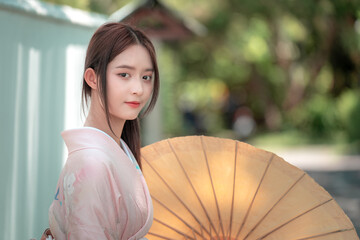 Young Woman in Traditional Attire with Parasol in Serene Setting