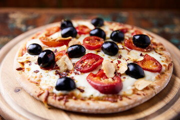 Pizza with salami and mozzarella cheese, jalapeno pepper and black olives. Wooden background. Soft focus. Close up.	