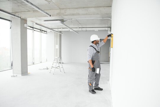 Construction worker observing and surveying wall alignment using water level
