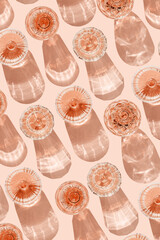 Stylish flat lay of rose wine crystal glasses casting shadows on pastel peach background. Minimal Top view sparkling alcohol drinking, champagne drinks at sun, wine aesthetic party concept