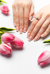 Woman showing french manicure near pink tulips on white background