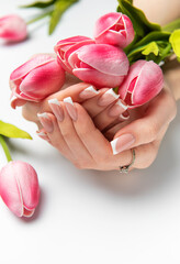 Woman holding pink tulips showing french manicure on white background