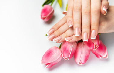 Woman showing french manicure and pink tulips on white background