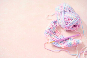 パステルカラーの毛糸でかぎ針編みをする編み物のイメージ