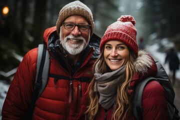 A happy couple dressed warmly smiles for the camera amidst a picturesque winter forest scene, highlighted by soft falling snow and a cozy atmosphere.