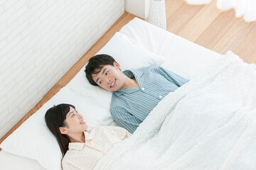 ベッドで話すパジャマ姿の夫婦