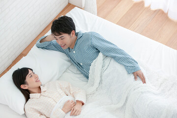 ベッドで話すパジャマ姿の夫婦