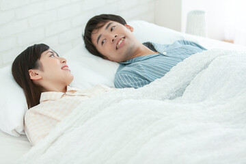 ベッドで話すパジャマ姿の夫婦