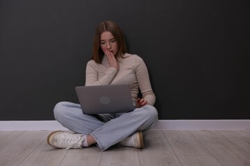 Cyber bullying. Upset teenage girl with laptop on floor indoors