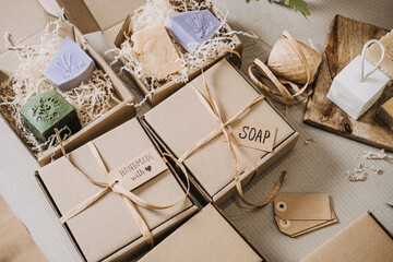 Kraft gift boxes labeled soap and handmade with love filled with artisanal bars and shredded filler. Handmade gifts, personalized packaging, conscious consumerism, slow gifting