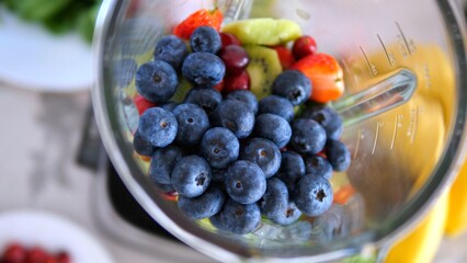 Colorful blueberries, strawberries, cherries, and kiwi pieces resting inside a blender, ready for mixing into a nutritious and delicious smoothie packed with vitamins and antioxidants