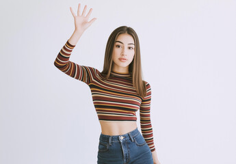 Full-Body Portrait of a Young Woman in Jeans and Striped Top – Artistic Pose with Open Palm and Raised Hand, White Background, Studio Shot, High-Resolution Fashion and Lifestyle Photography