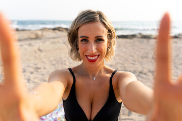 Happy tourist taking selfie on sandy beach with ocean view