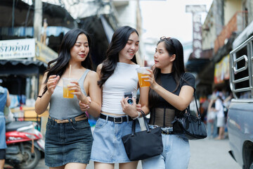 Young women drinking juice and walking in a street market in thailand © Phimwilai