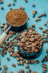 Coffee beans and scoop on blue background with scattered beans
