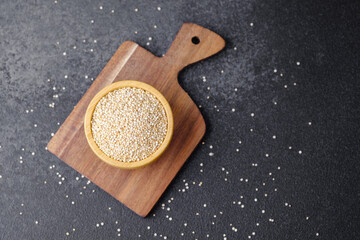 Quinoa seeds in wooden bowl on cutting board