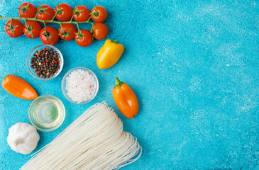noodles, bell peppers, tomatoes and spices on blue background