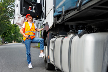 Portrait young adult happy smiling woman climbing cabin heavy truck driver cargo vehicle. Female person girl professional job career working driving freight engine lorry. Logistics industry