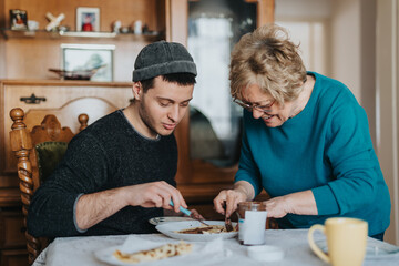 A senior woman and a young man spending quality time preparing food together at a family dining...