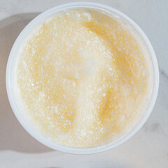 close up of vitamin C jelly cream in open glass jar on marble background. Presentation of skin care beauty products. Swirl of cream, promotion product showcase