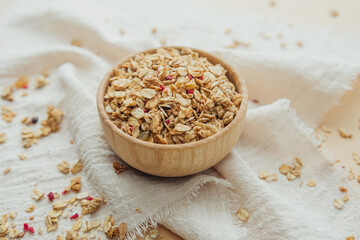 Granola in wooden bowl on soft white cloth background