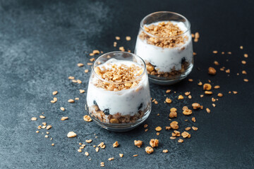 Parfaits with granola and yogurt in glass on dark  background