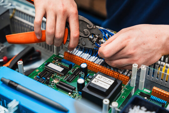 Technician hands working with electrical wiring in control panel in workshop