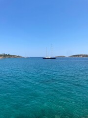Obraz premium Sailing yacht in calm turquoise sea under clear blue sky!