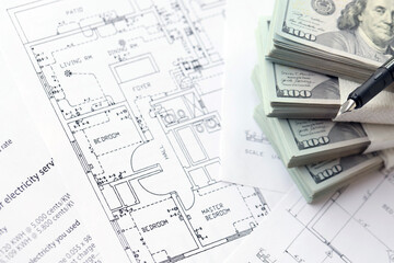 Big amount of US dollars money bills with pen and planning blueprints of residential building project