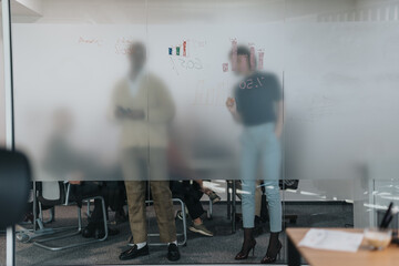 A group of colleagues collaborate in an office setting, brainstorming ideas with diagrams on a...