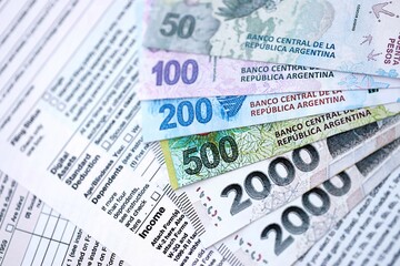 Argentine pesos money bills in big amount lies on table with pen and tax forms close up