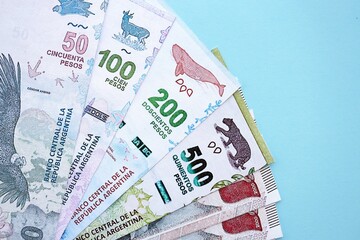 Argentine pesos money bills in big amount lies on teal color table close up