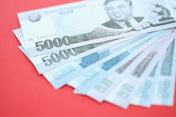 North Korean won money bills in big amount lies on red color table close up