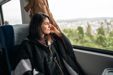 Young woman traveling by train and looking out the window .