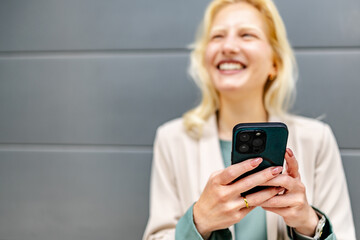 Young woman with albinism smiles while using her smartphone in a modern indoor setting during...