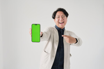 A man is holding a green phone and pointing to it. He is smiling. The phone is green and has a green screen
