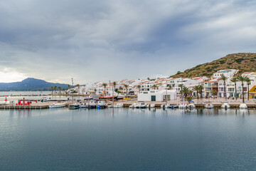 Charming Mediterranean Coastal Village With White Buildings And Boats. Menorcan Architecture, Balearic Islands, Spanish Island Life, Travel Destination