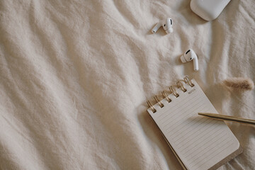 Flat Lay of Notebook and Earbuds on Soft Fabric