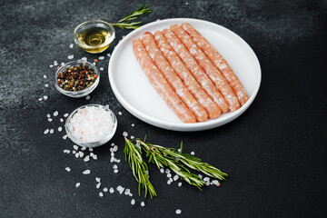 Fresh pork sausages on white plate with herbs and seasonings