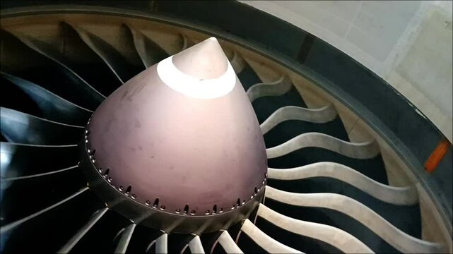 Close-up of aircraft turbofan engine fan blades rotating slowly after engine shutdown