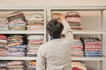 A man is looking at a shelf full of clothes