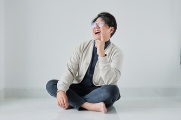 A man is sitting on the floor with his legs crossed and a white jacket on