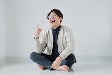 A man is sitting on the floor with his hands on his knees