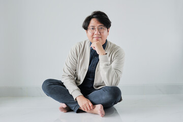 A man is sitting on the floor with his hands on his knees