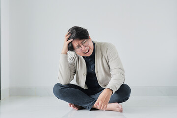 A man is sitting on the floor with his head in his hands