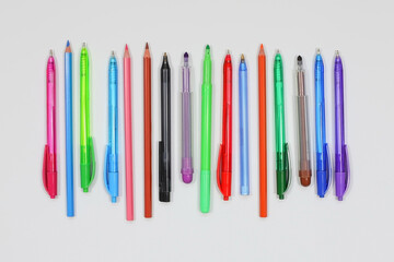 Top view of collection of pens, pencils and markers on white background desk for mockup