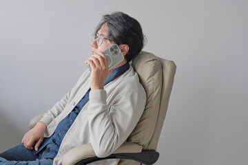 A man is sitting in a chair and talking on his cell phone